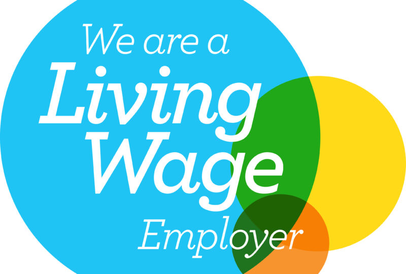 White text over a large blue circle reads we are a living wage employer to the right of the large blue circle or a smaller yellow and orange circle which overlap to create shaded colours.