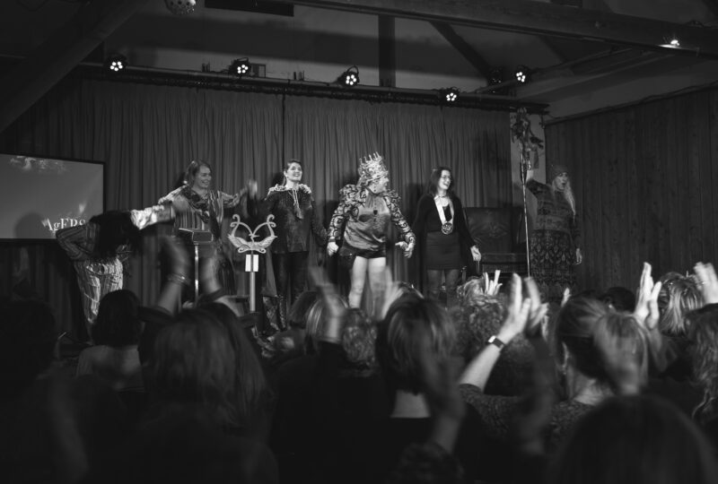 Black and white photo of the Queenagers cast bowing in front of a cheering audience